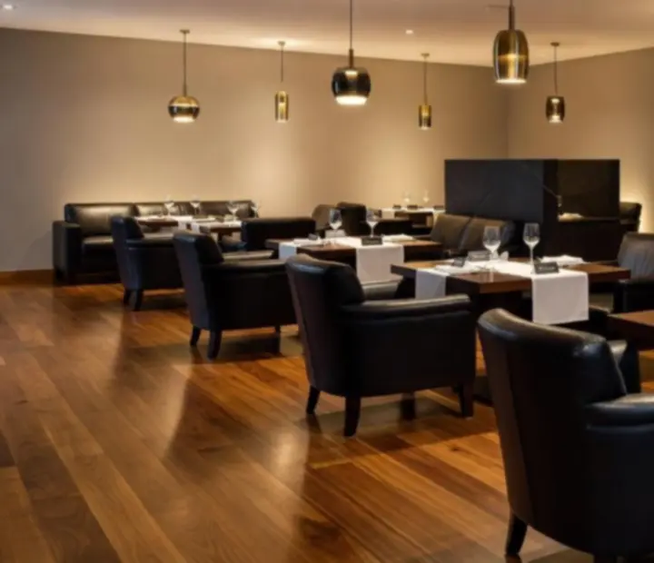 Luxurious private event lounge with Australian hardwood, black stone and warm ambient lighting.